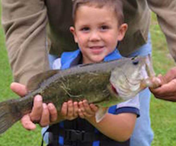 little boy holding up a fish